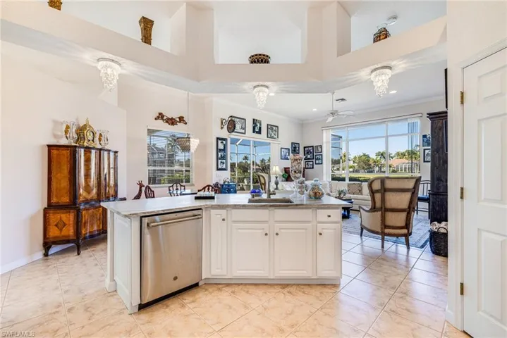 Kitchen with white cabinetry, dishwasher, a ceiling fan, a center island with sink, and crown molding