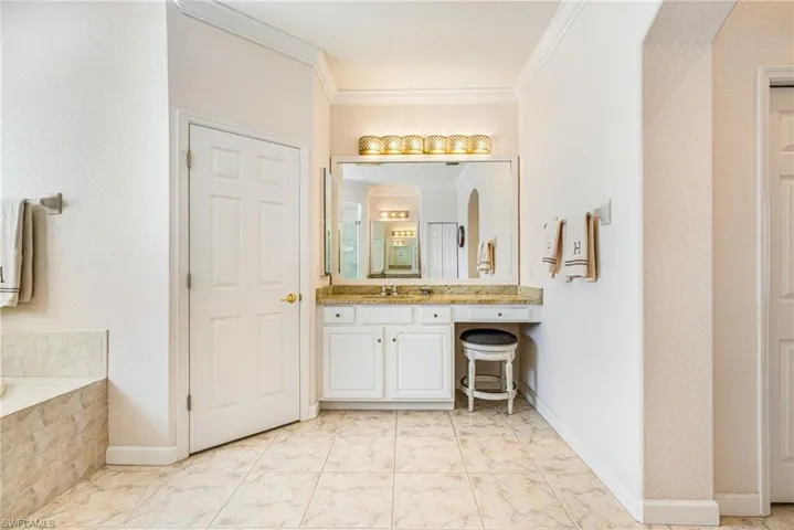 Bathroom featuring crown molding, vanity, and a bath
