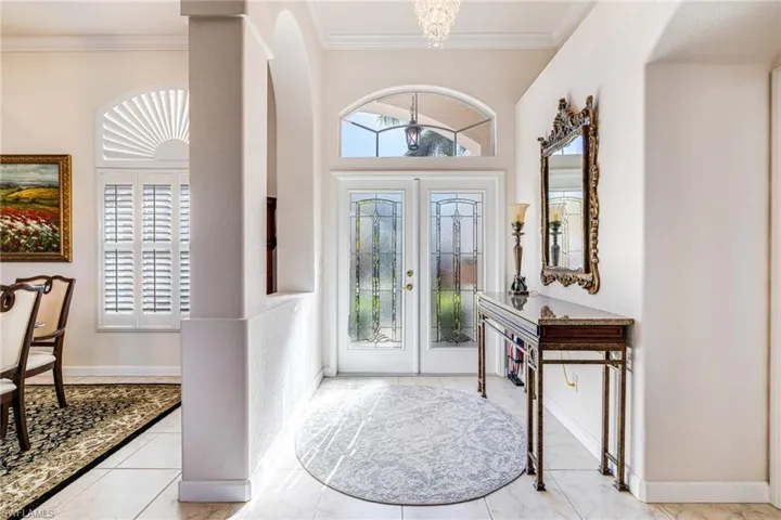 Foyer entrance featuring ornamental molding, a high ceiling, and arched walkways