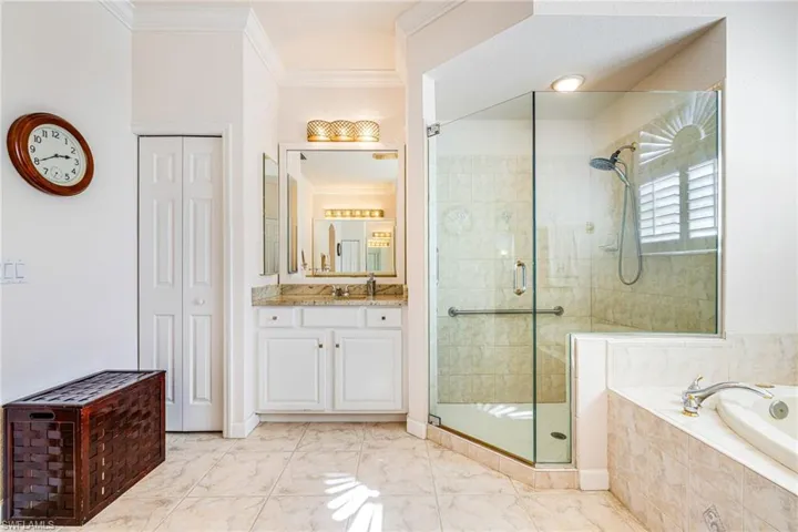 Bathroom featuring a closet, ornamental molding, a shower stall, vanity, and a garden tub