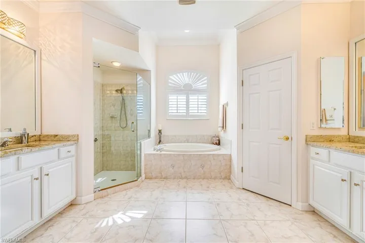 Bathroom with vanity, a stall shower, a garden tub, and ornamental molding