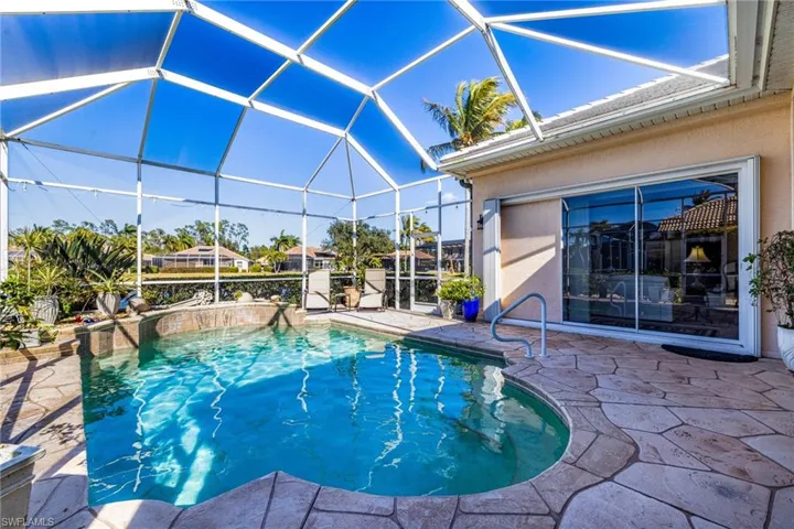 Swimming pool featuring a patio, a sunroom, and glass enclosure