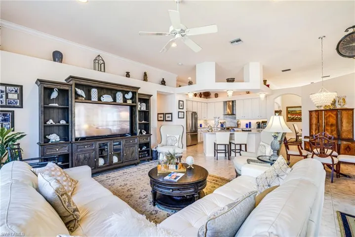 Living area featuring ceiling fan, arched walkways, light tile patterned floors, and suspended lighting