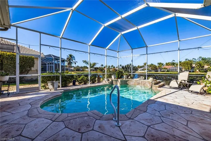 Outdoor pool featuring a sunroom, glass enclosure, and a patio area