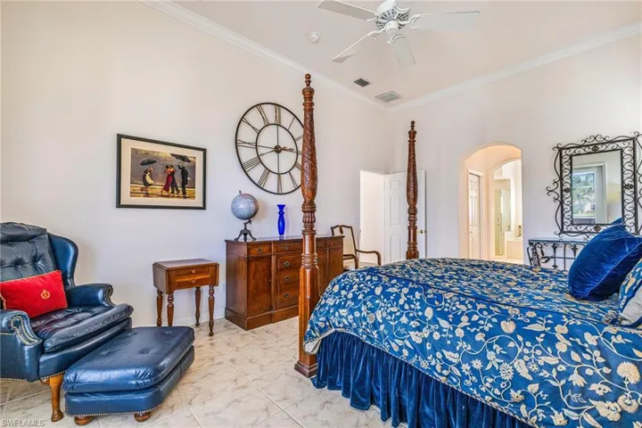 Bedroom featuring arched walkways, crown molding, and a ceiling fan