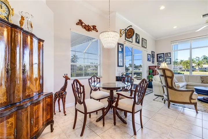 Dining area with ornamental molding, healthy amount of natural light, hanging lights, light tile patterned floors, and a ceiling fan