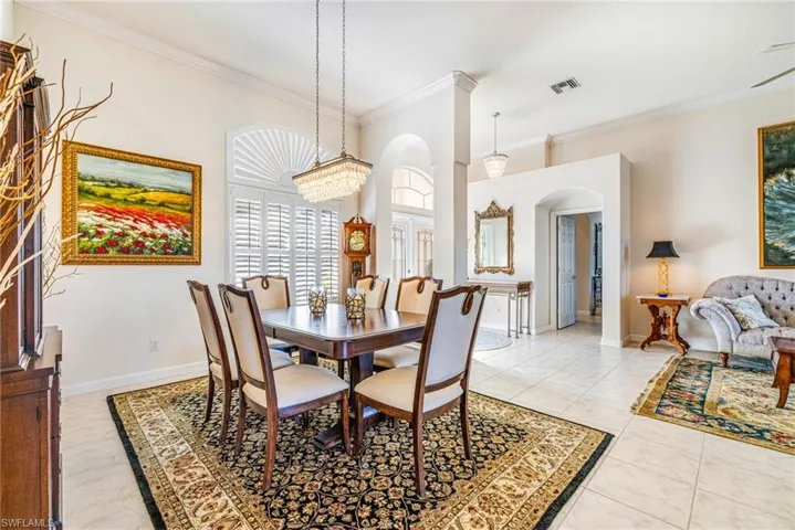 Dining area with arched walkways, crown molding, and light tile patterned floors