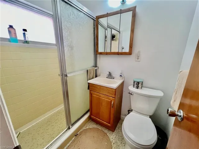 Primary bathroom with terrazzo floor, vanity, toilet, and a walk in shower.