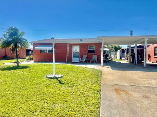 View of front of home with an attached carport, a front lawn, and extra long driveway for plenty of cars.