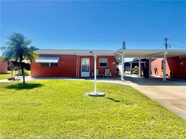View of front of home featuring a carport, concrete driveway, and a front yard