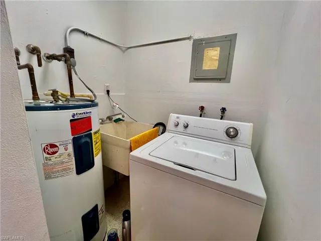 Laundry area featuring electric panel, a sink, water heater, washer / dryer, and laundry area