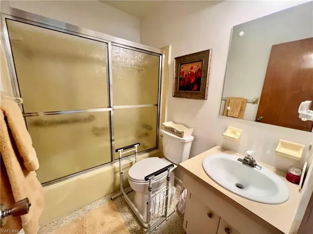 Bathroom featuring vanity, toilet, and shower / bath combination with glass door