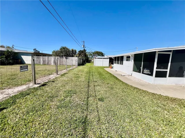 View of yard featuring fence and a screened lanai.