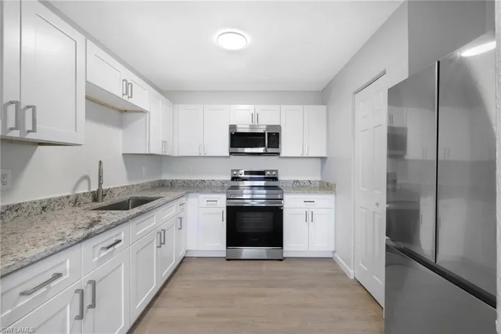 Kitchen with white cabinetry, appliances with stainless steel finishes, and sink