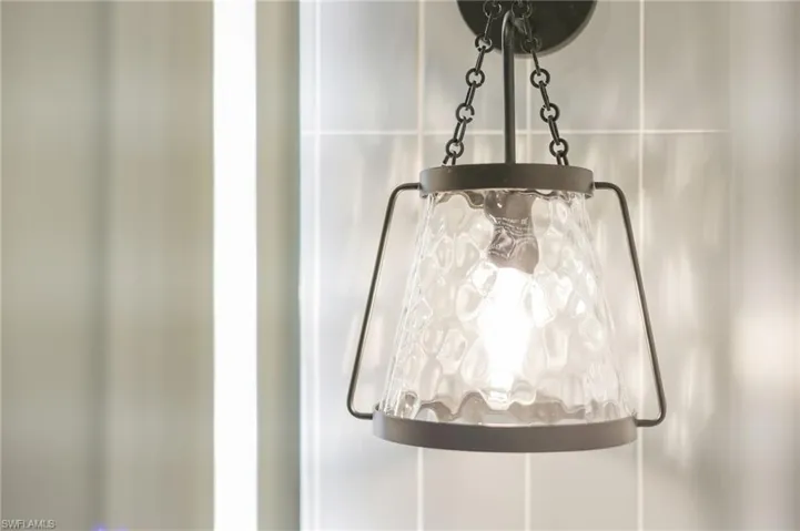Architectural wall sconce with textured glass and a dark-toned chain suspension