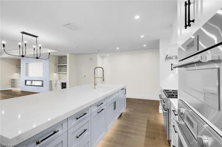 Expansive kitchen island with a light-toned countertop, light blue cabinetry, and a gold-finish faucet
