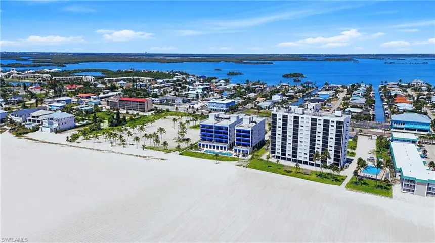 Expansive beachfront property featuring direct beach access, multiple high-rise buildings, an outdoor swimming pool, and proximity to waterwaysExpansive land parcel with direct beach access, surrounded by established buildings and roadways - Virtually Edited Image