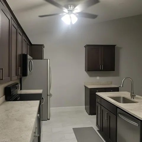 Kitchen with stainless steel appliances, dark brown cabinetry, and a ceiling fan