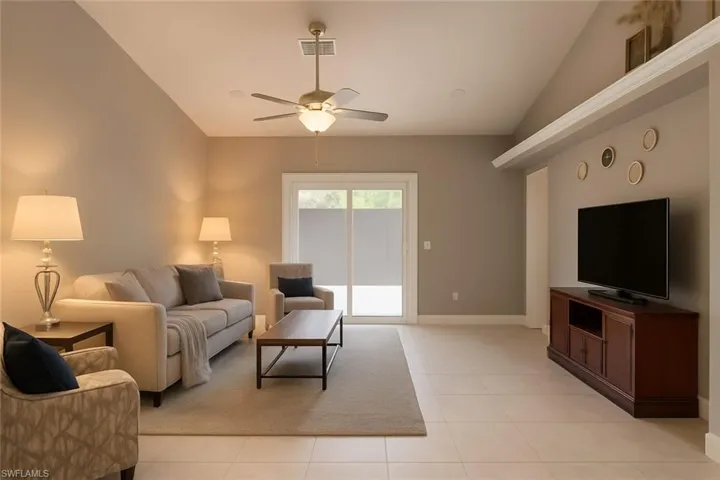 Living room with lofted ceiling, light tile patterned floors, and a ceiling fan