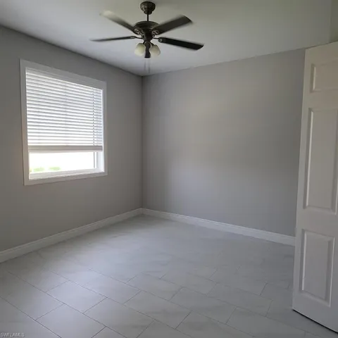Empty room featuring ceiling fan and light tile patterned floors
