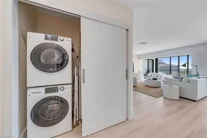 Laundry area featuring stacked washing machine and dryer and light wood-style flooring