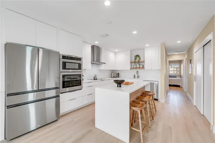 Kitchen featuring stainless steel appliances, modern cabinets, white cabinets, and recessed lighting