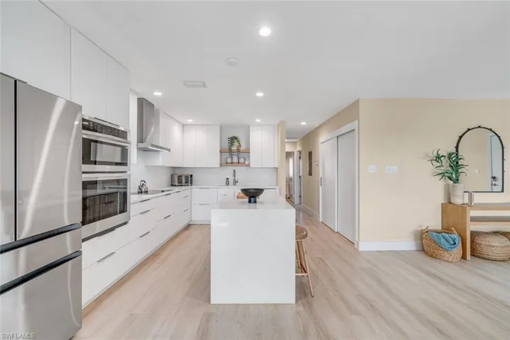 Kitchen with modern cabinets, a kitchen breakfast bar, white cabinets, appliances with stainless steel finishes, and open shelves