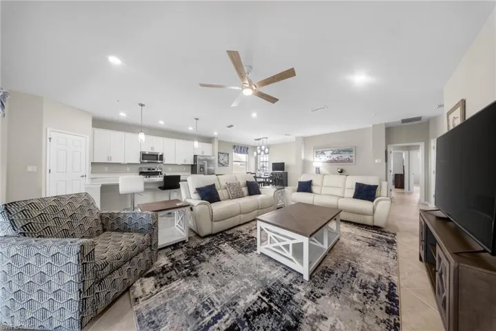 Living room with a ceiling fan, recessed lighting, and light tile patterned floors