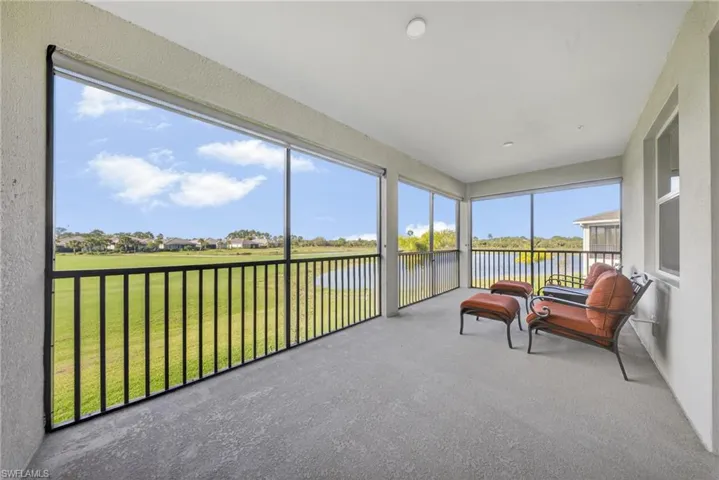 Sunroom / solarium featuring a water view, carpet flooring, a residential view, and a textured wall
