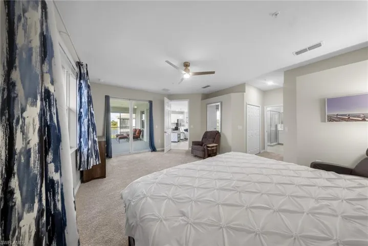 Bedroom with light colored carpet, access to outside, ceiling fan, and ensuite bath