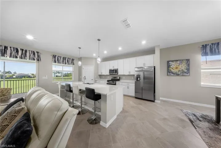 Kitchen featuring stainless steel appliances, plenty of natural light, white cabinetry, and a breakfast bar area