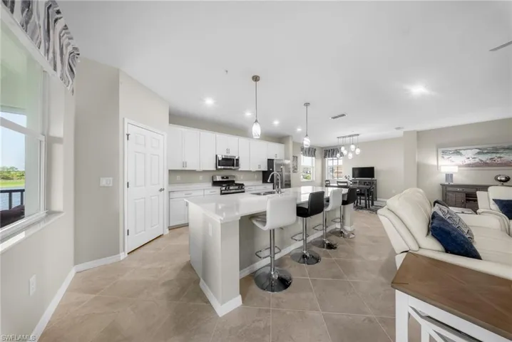 Kitchen with white cabinetry, an island with sink, a breakfast bar area, open floor plan, and stainless steel appliances