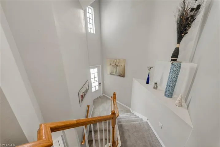 Stairway with a high ceiling, healthy amount of natural light, and carpet