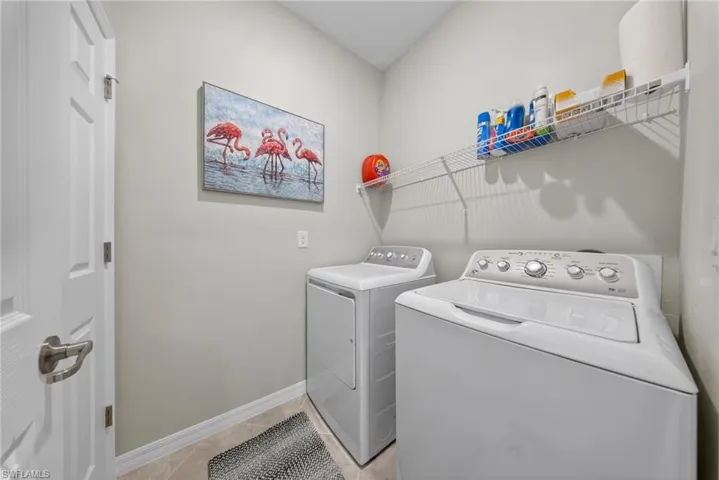Laundry room with washer and clothes dryer and light tile patterned floors