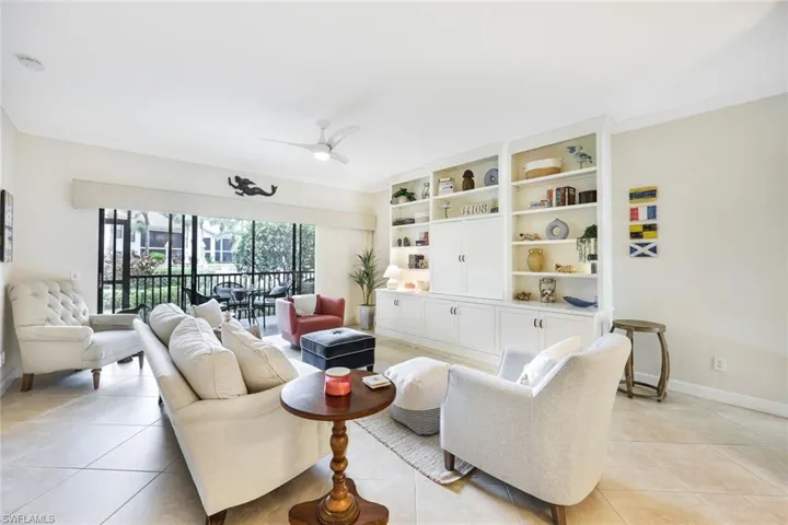 Tiled living room with ceiling fan, ornamental molding, and built in features