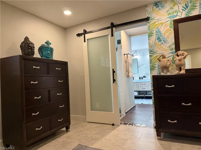 Bedroom featuring a barn door, connected bathroom, and recessed lighting