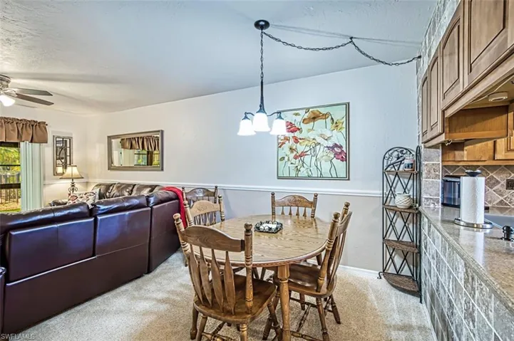 Dining area featuring light carpet and ceiling fan with notable chandelier