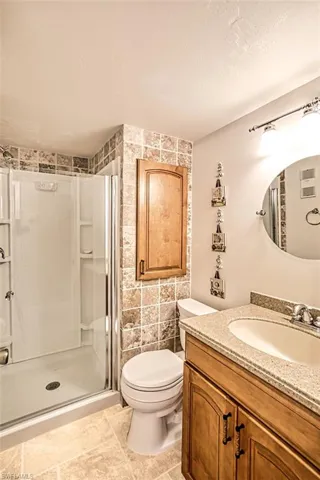 Bathroom with tile walls, walk in shower, tile patterned floors, toilet, and vanity