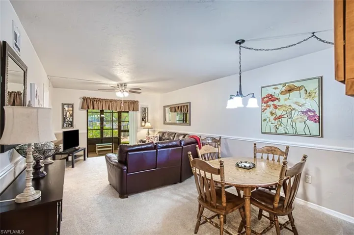 Carpeted dining room with ceiling fan with notable chandelier