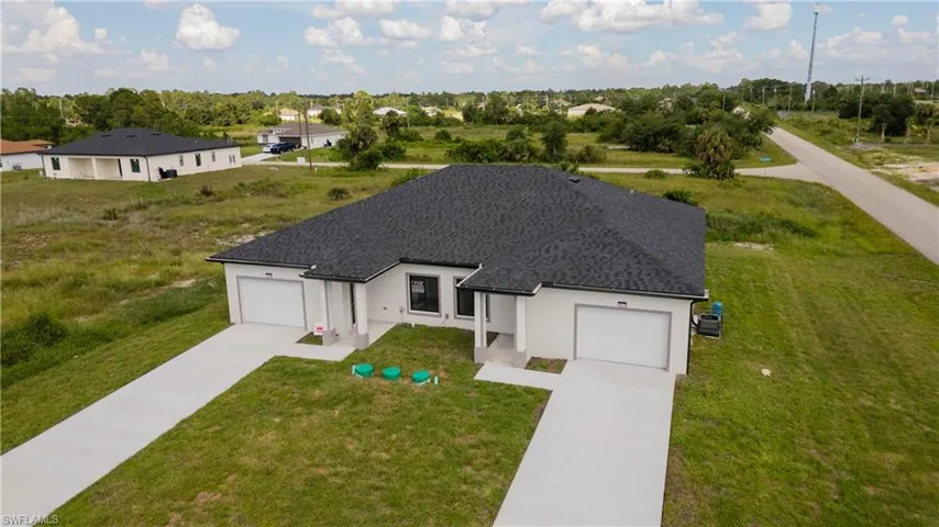 View of front of house featuring stucco siding, a garage, and a front lawn