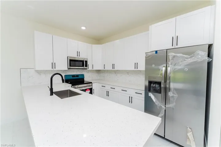 Kitchen with stainless steel appliances, a peninsula, white cabinets, tasteful backsplash, and recessed lighting