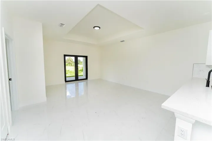 Spare room featuring a tray ceiling, french doors, and light marble finish flooring
