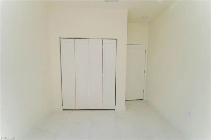 Unfurnished bedroom featuring light marble finish flooring and a closet