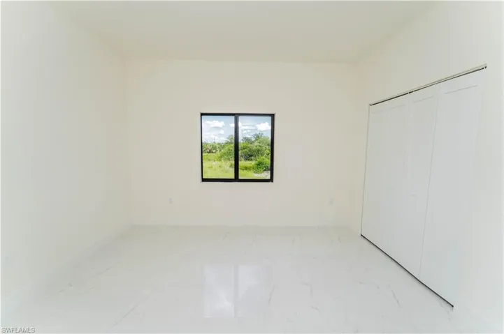 Unfurnished bedroom featuring light marble finish flooring and a closet