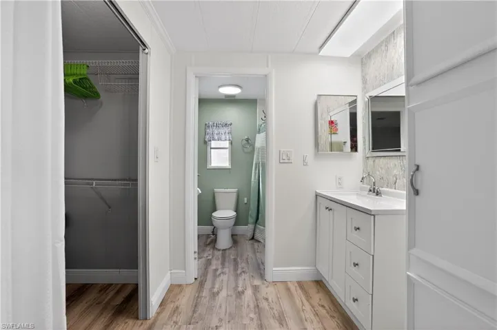 Full bathroom featuring vanity, a stall shower, a spacious closet, and light wood-style flooring