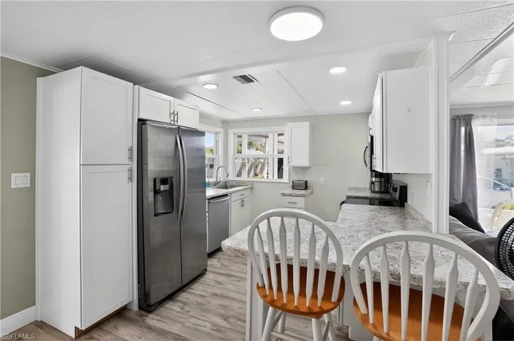 Kitchen featuring stainless steel appliances, white cabinetry, light wood-type flooring, a peninsula, and a breakfast bar