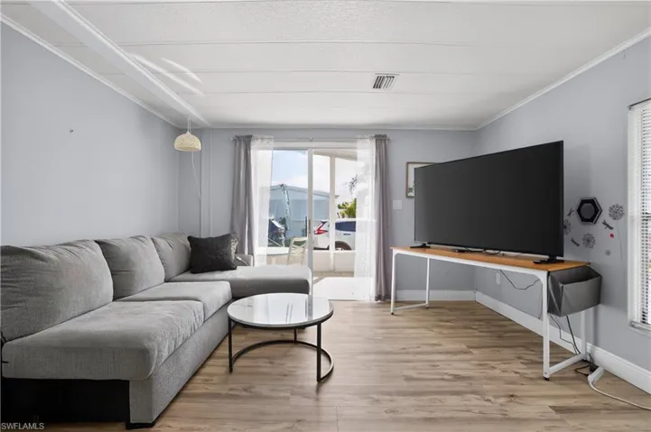 Living room with ornamental molding and light wood-style flooring