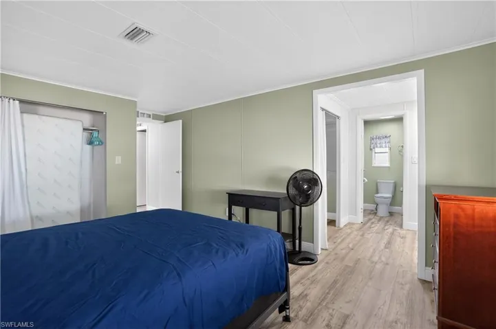 Bedroom featuring wood finished floors, ornamental molding, and a closet