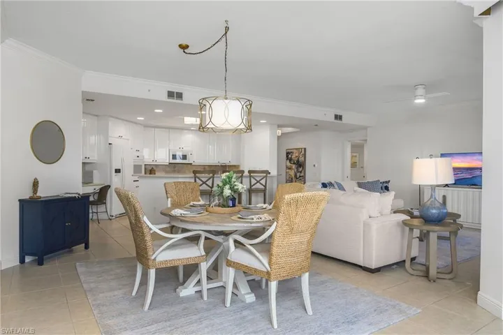 Dining space with light tile patterned floors, ceiling fan with notable chandelier, and ornamental molding
