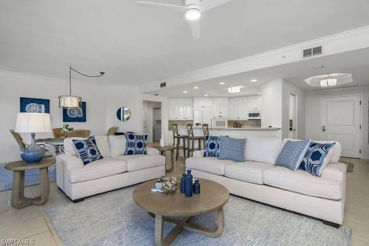 Living room featuring light tile patterned flooring, ceiling fan, and ornamental molding